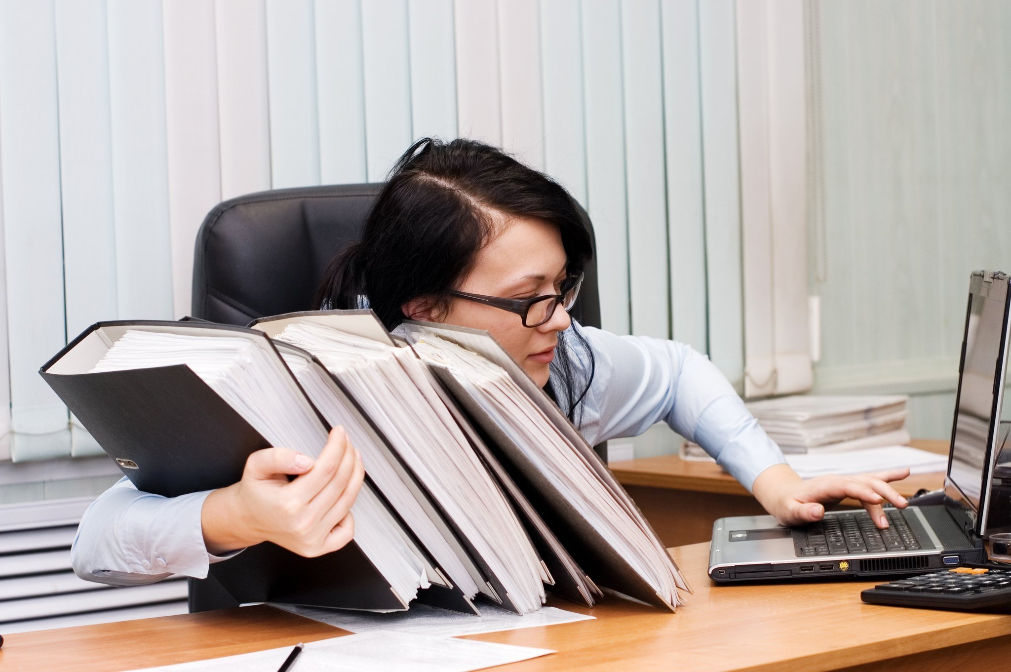 Скука на работе. Женщина в офисе с бумагами. Бухгалтер за компьютером. Рабочее место секретаря. Офисный работник с бумагами.