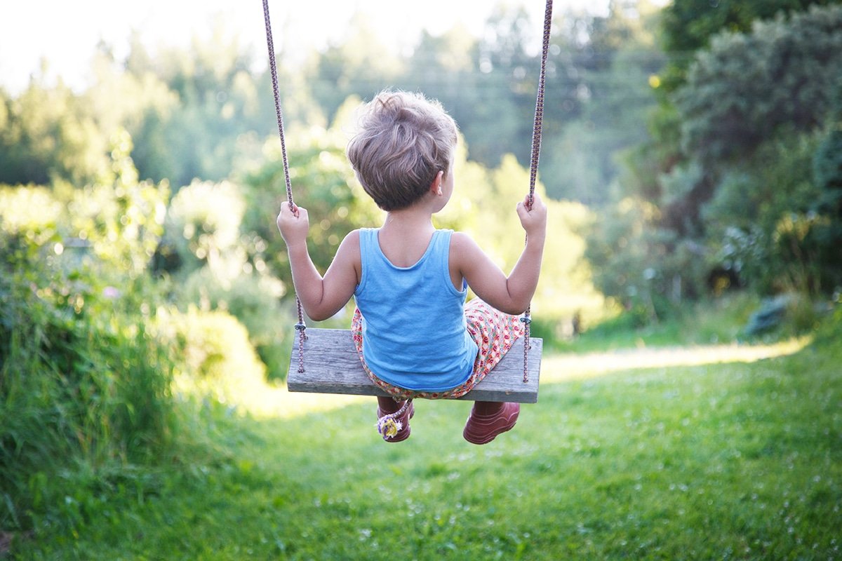 Ребенок на качелях со спины