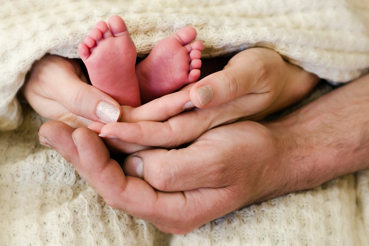 Мама день ноги. Пяточки младенца в руках. Ножки малыша в руках. Ножки ребенка в руках родителей. Детская ножка в руках.