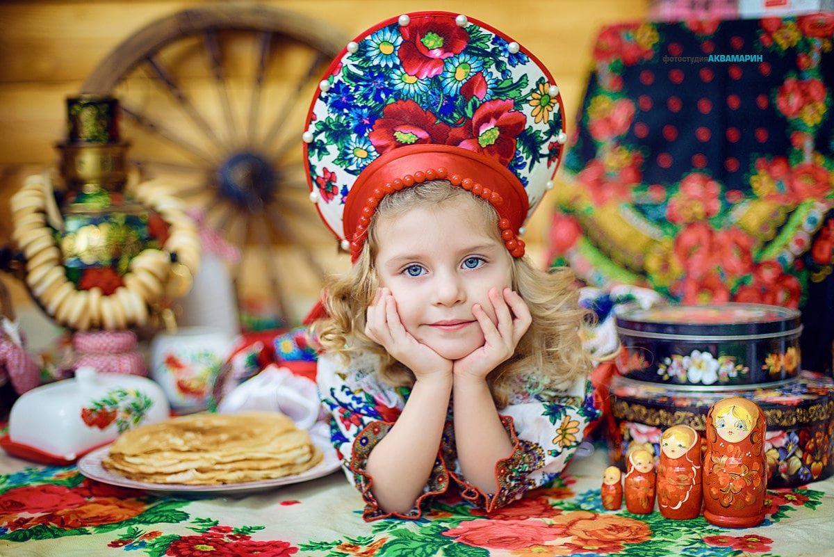 Улыбающиеся дети по-масленичному одетые сидят рядом с самоваром