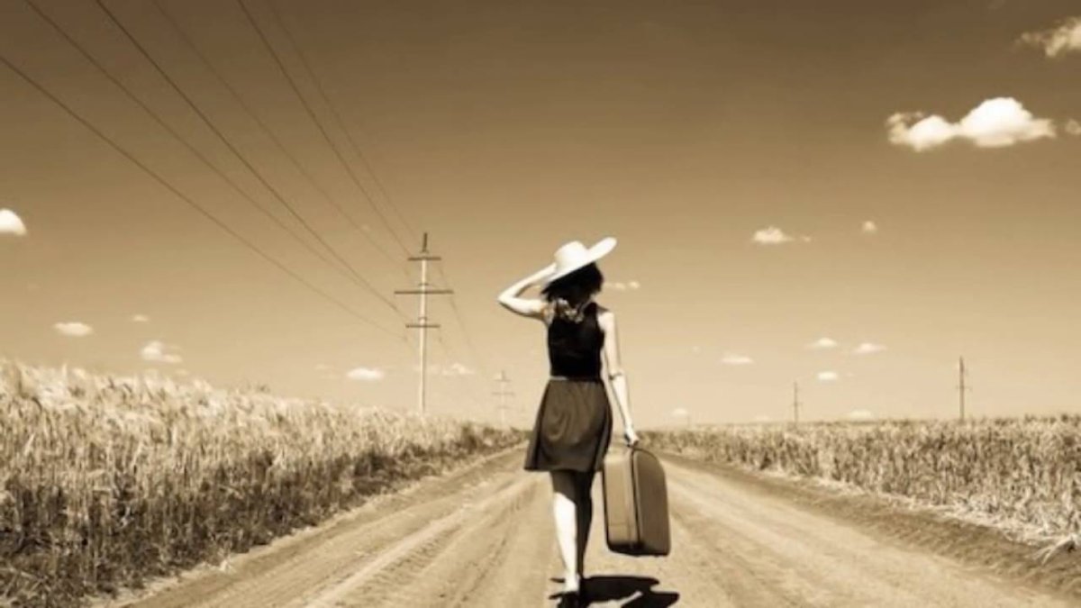 Девушка с чемоданом на дороге