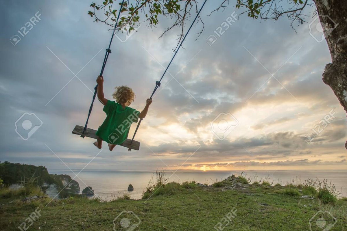 Мальчик на качелях спиной Сток