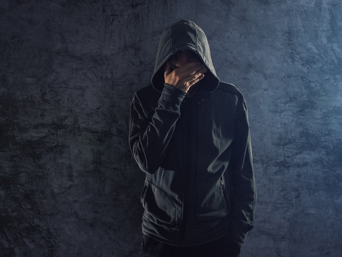 Мужчина в капюшоне сидит