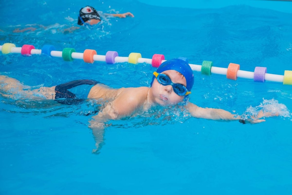 Мальчик плавает в бассейне