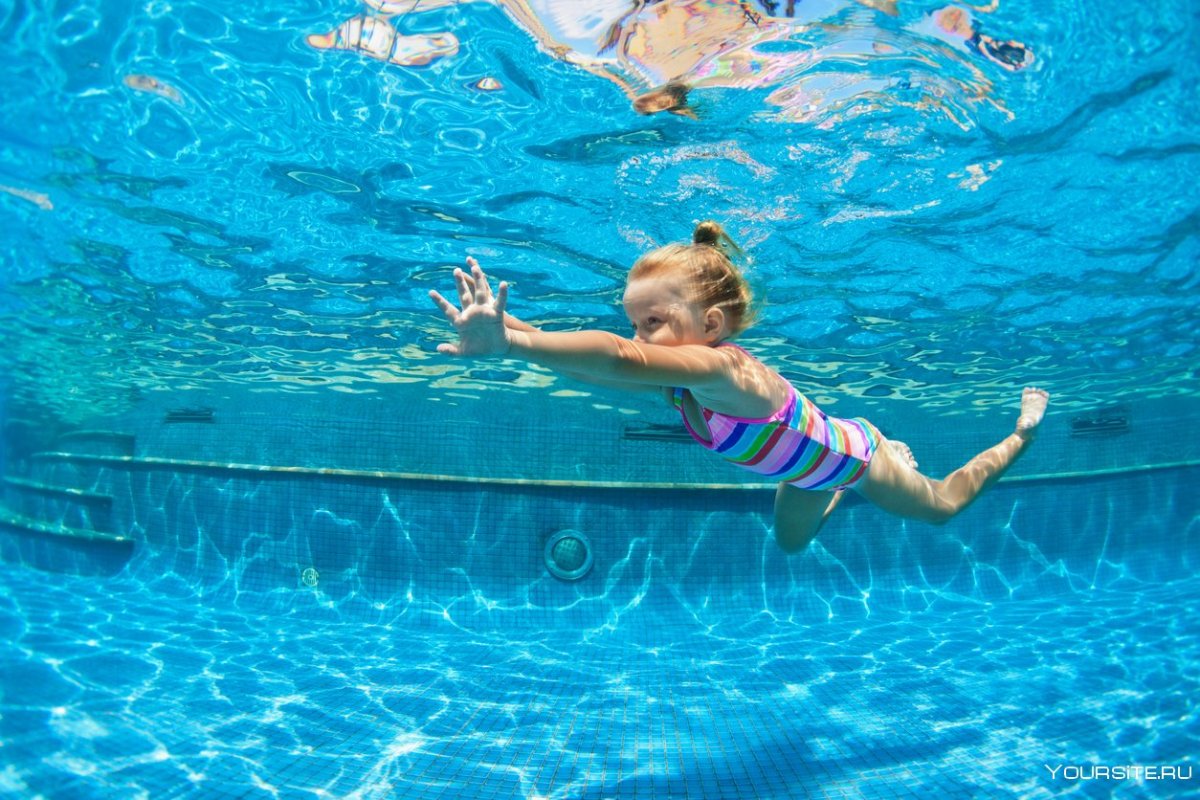 Маленькая девочка плавает в бассейне