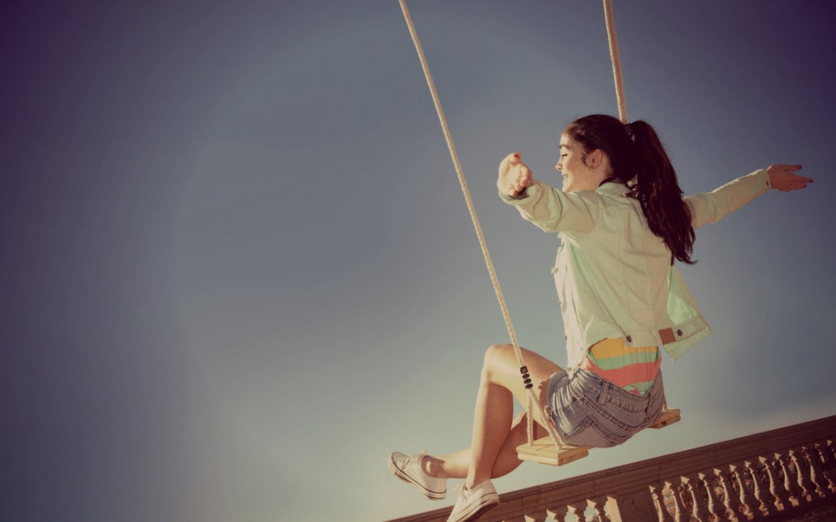 Счастливая девушка на качелях