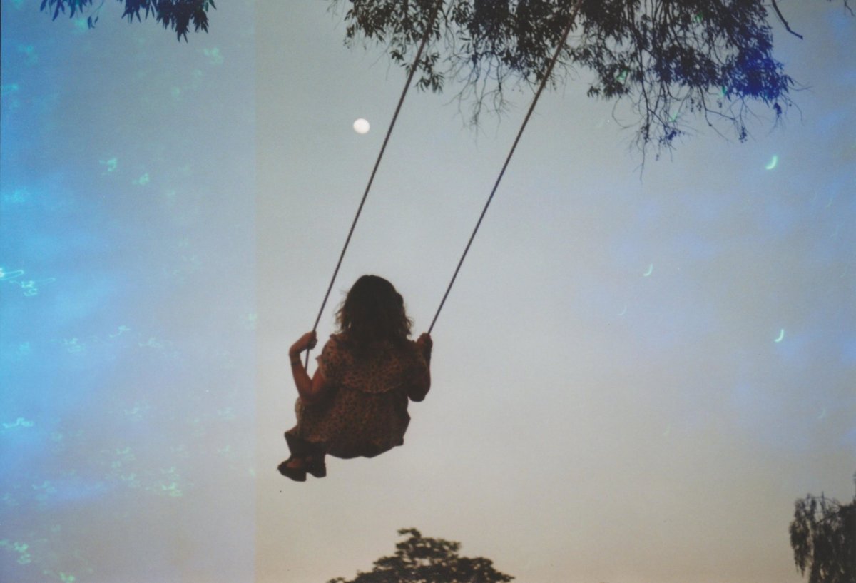 Девушка на качелях со спины