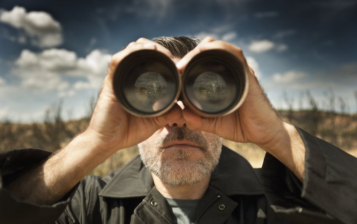 Девушка с биноклем на белом фоне