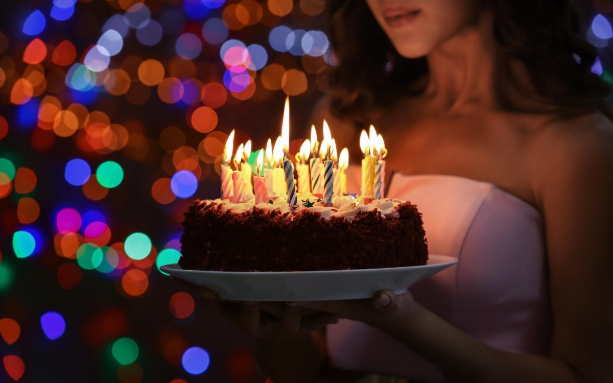 Девушка задувает свечи на торте