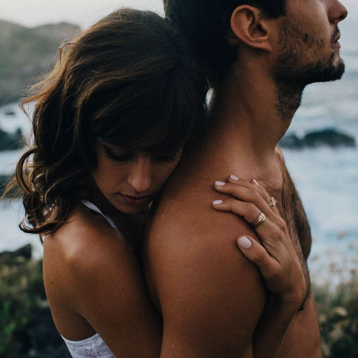 Парень сидит сзади девушки и обнимает