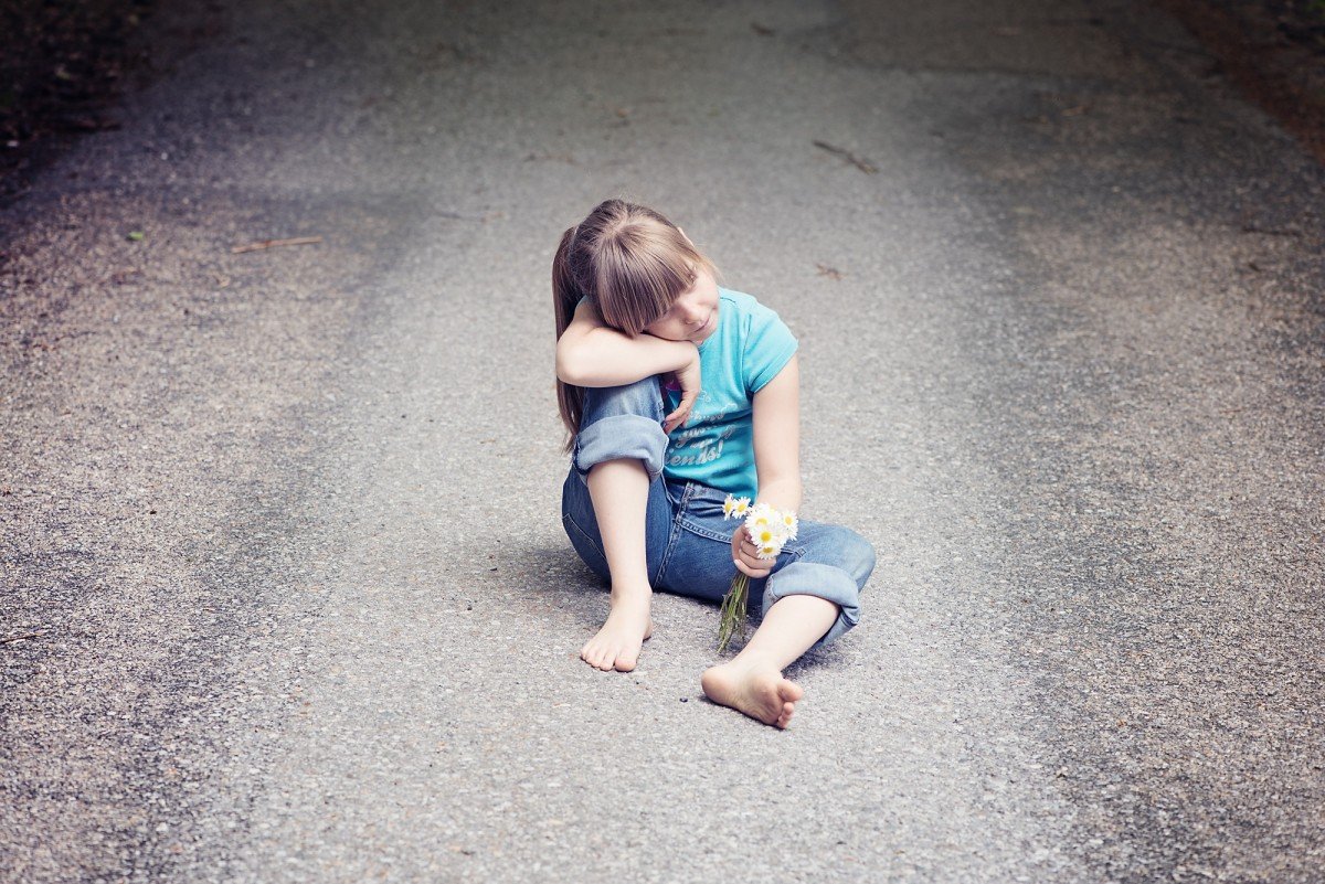 Девочка сидит на дороге