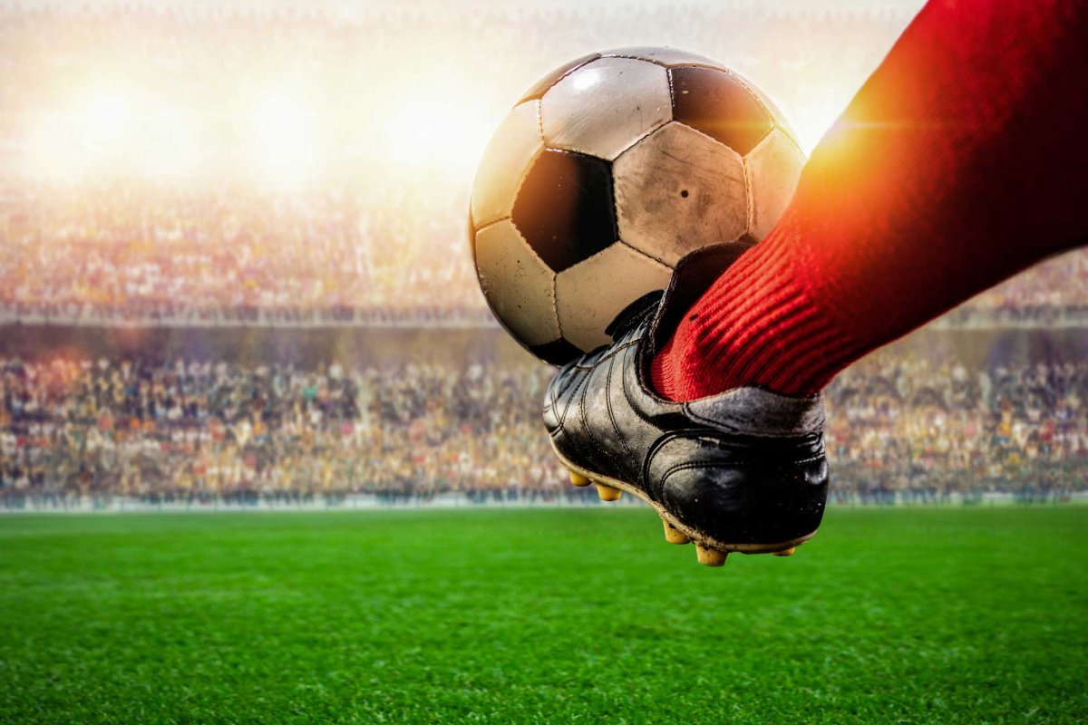 Футбольный мяч и нога на фоне арены