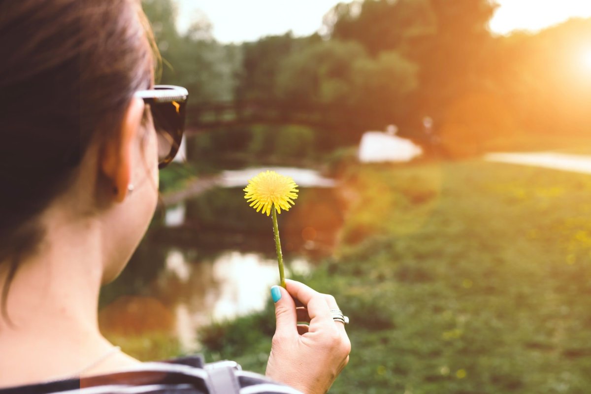 Девушка дует на одуванчик